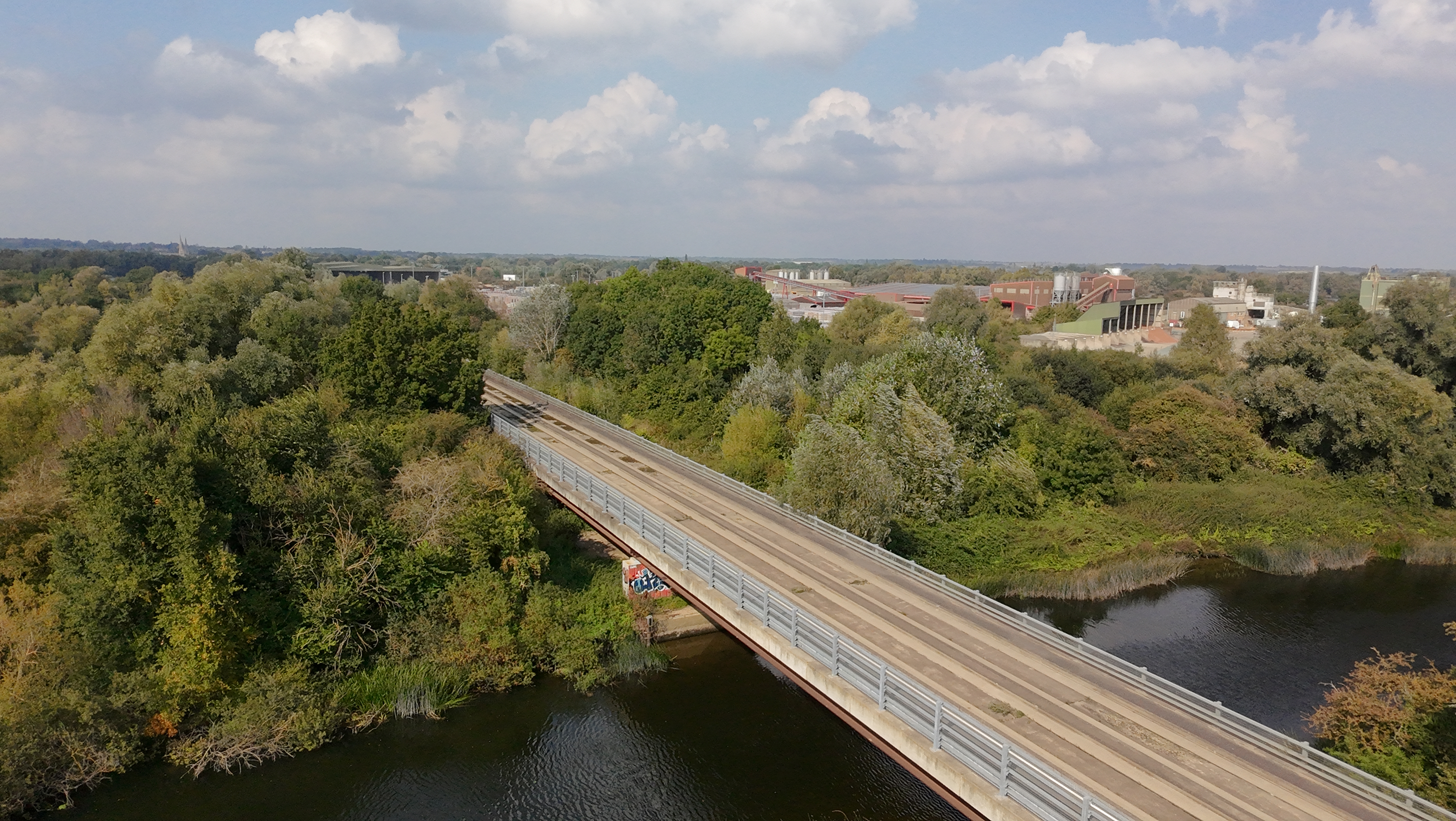 View of a bridge crossing a river fringed by trees taken by DJI Neo.