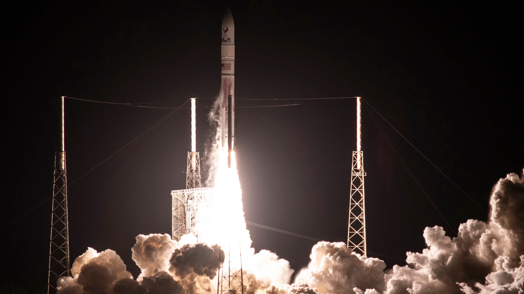 a white rocket launches into a night sky