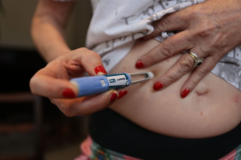 Close up view of a person giving themselves an injection.