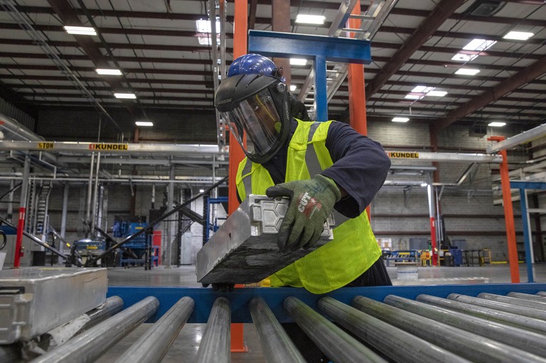 An Ascend Elements lead discharge technician places electric vehicle batteries on a conveyer belt in Georgia