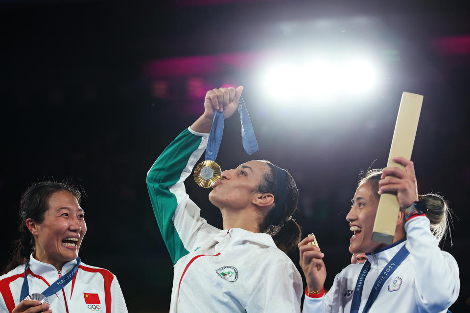 PARIS, FRANCE - AUGUST 09: Silver Medallist Liu Yang of Team People's Republic of China (L) Bronze Medallist Janjaem Suwannapheng of Team Thailand (obscured) and Bronze Medallist Nien Chin Chen of Team Chinese Taipei (R) react as Gold Medallist Imane Khelif of Team Algeria (C) kisses her medal during the Boxing Women's 66kg medal ceremony after the Boxing Women's 66kg Final match on day fourteen of the Olympic Games Paris 2024 at Roland Garros on August 09, 2024 in Paris, France.  (Photo by Richard Pelham/Getty Images)