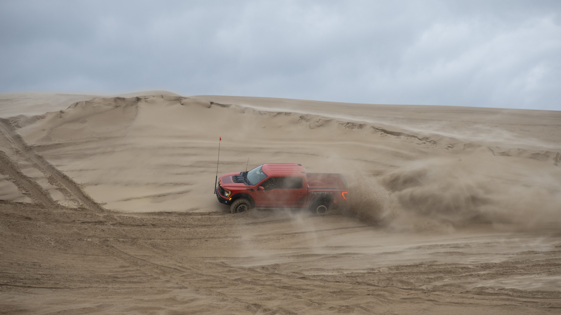 2023 Ford F-150 Raptor R doing a wall ride on a sand dune.