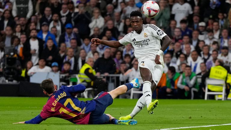 Real Madrid's Vinicius Junior is challenged by Barcelona's Marc Casado