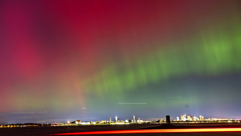 Northern lights over the Boston skyline shine red and green.