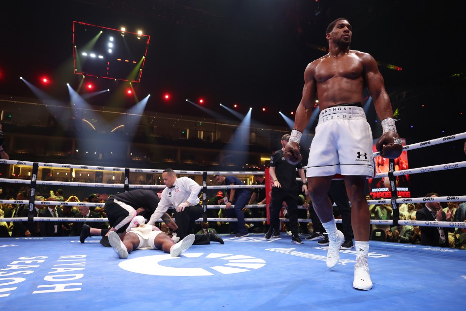 Anthony Joshua standing over a fallen opponent in a boxing match.