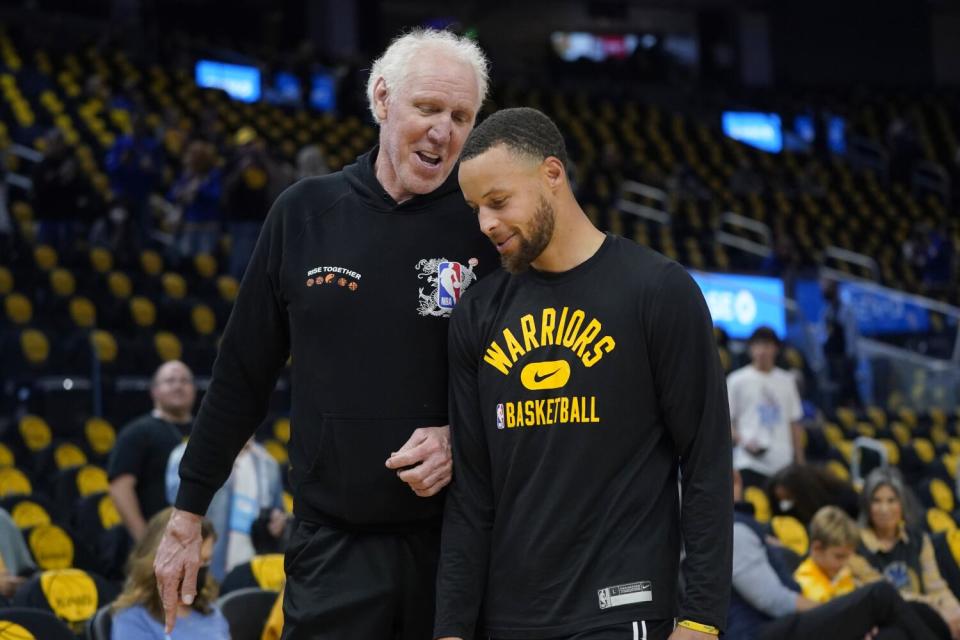 Bill Walton, left, talks with Golden State Warriors guard Stephen Curry before a playoff game in May 2022.