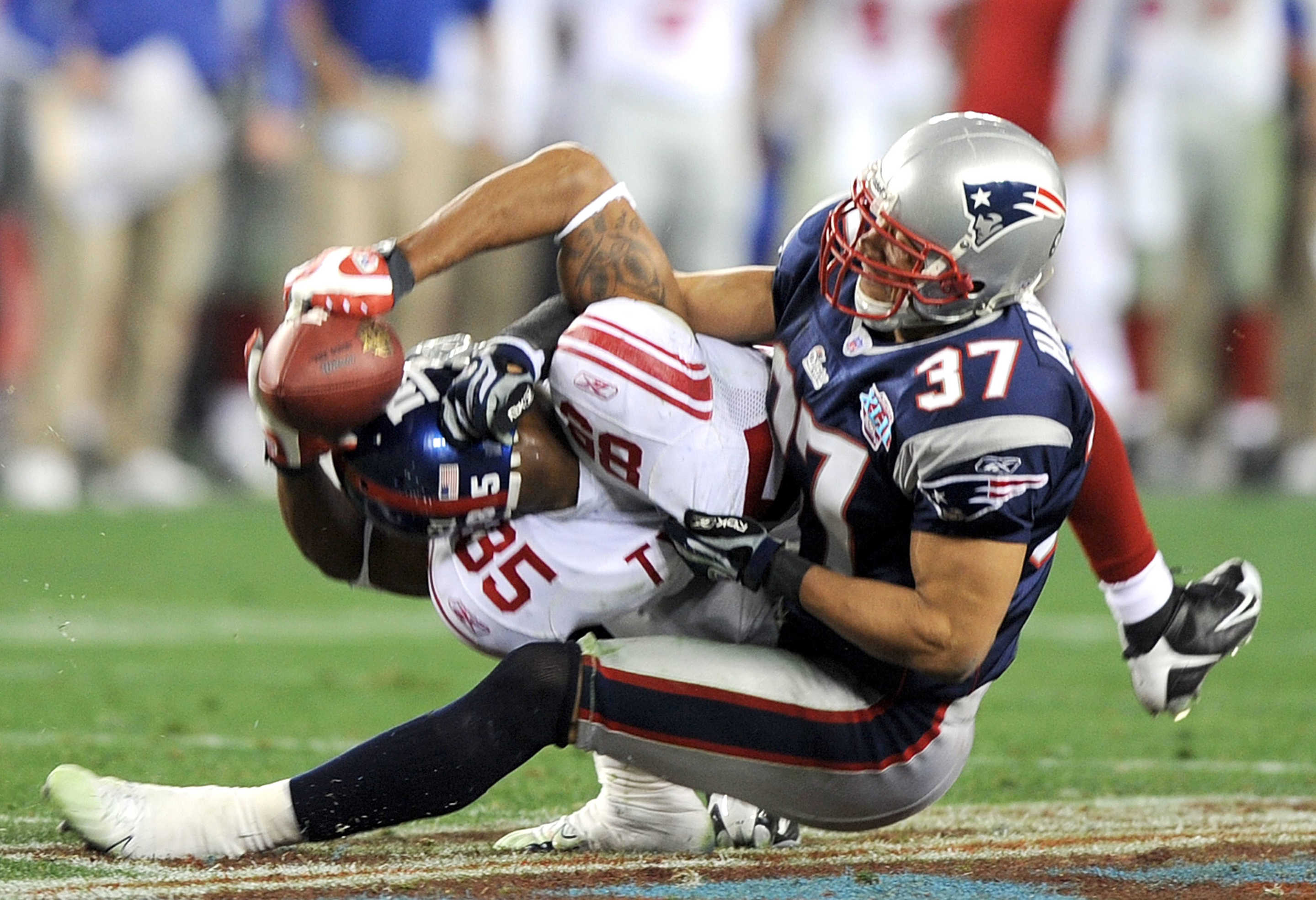 New York Giants' receiver David Tyree (85) holds onto the ball as he is brought down by the New England Patriots' Rodney Harrison (37) in a 17-14 Giants victory in Super Bowl XLII at University of Phoenix Stadium in Glendale, Arizona, on Sunday, February 3, 2008.  (Photo by Karl Mondon/MCT/Tribune News Service via Getty Images)