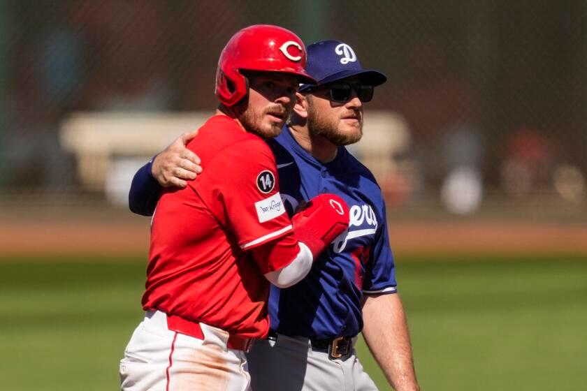 Cincinnati Reds' Gavin Lux, left, hugs Los Angeles Dodgers third baseman Max Muncy.