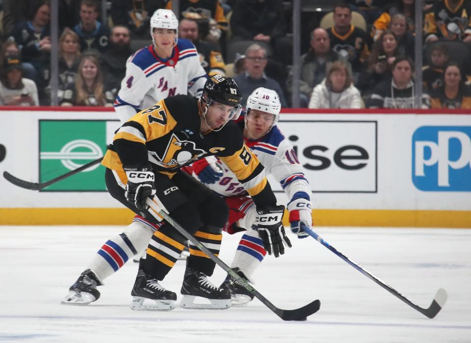 Feb 23, 2025; Pittsburgh, Pennsylvania, USA; Pittsburgh Penguins center Sidney Crosby (87) shields the puck from New York Rangers left wing Artemi Panarin (10) during the third period at PPG Paints Arena. (Charles LeClaire-Imagn Images)