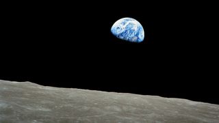 a blue and white planet seen from the surface of a grey, dusty moon