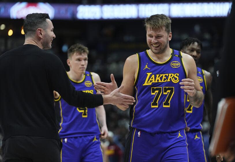 Los Angeles Lakers head coach JJ Redick, left, congratulates guard Luka Doncic.