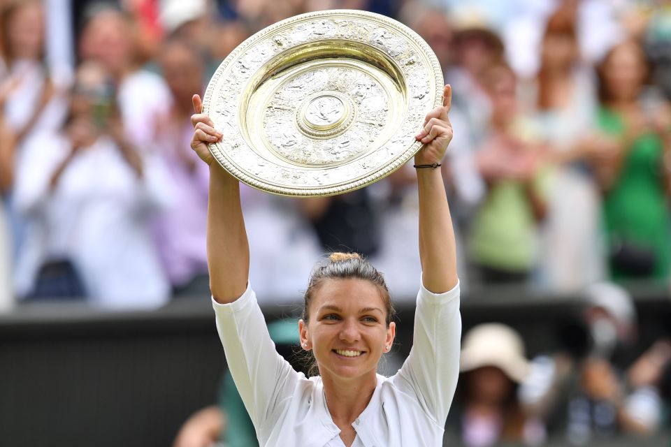 Simona Halep holding the Venus Rosewater Dish trophy aloft.