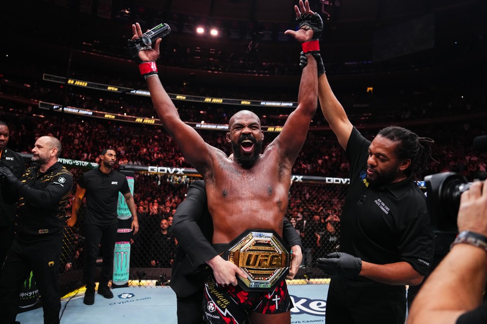 Jon Jones victorious at UFC 309, holding the championship belt.