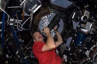 a man in a red shirt in a round compartment surrounded by windows