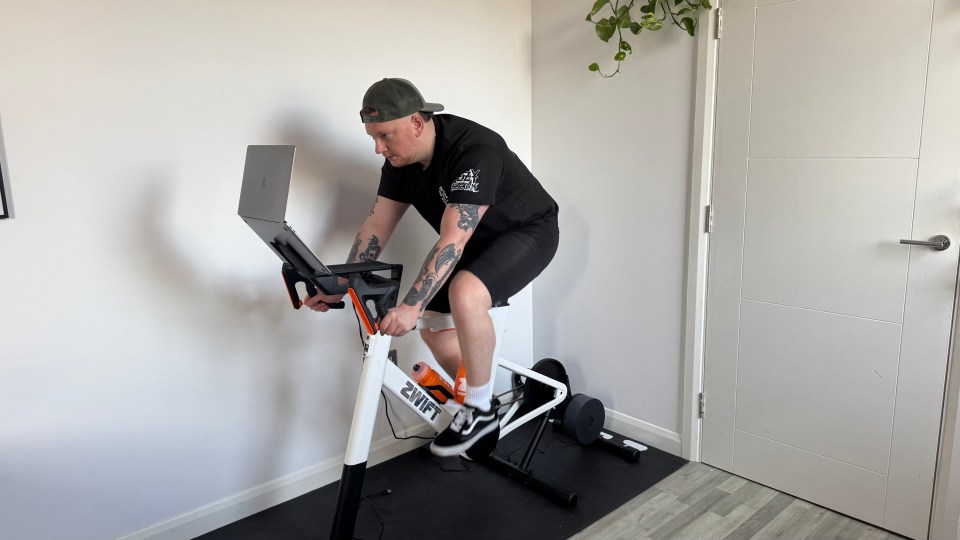 Person using a Zwift bike with a laptop.