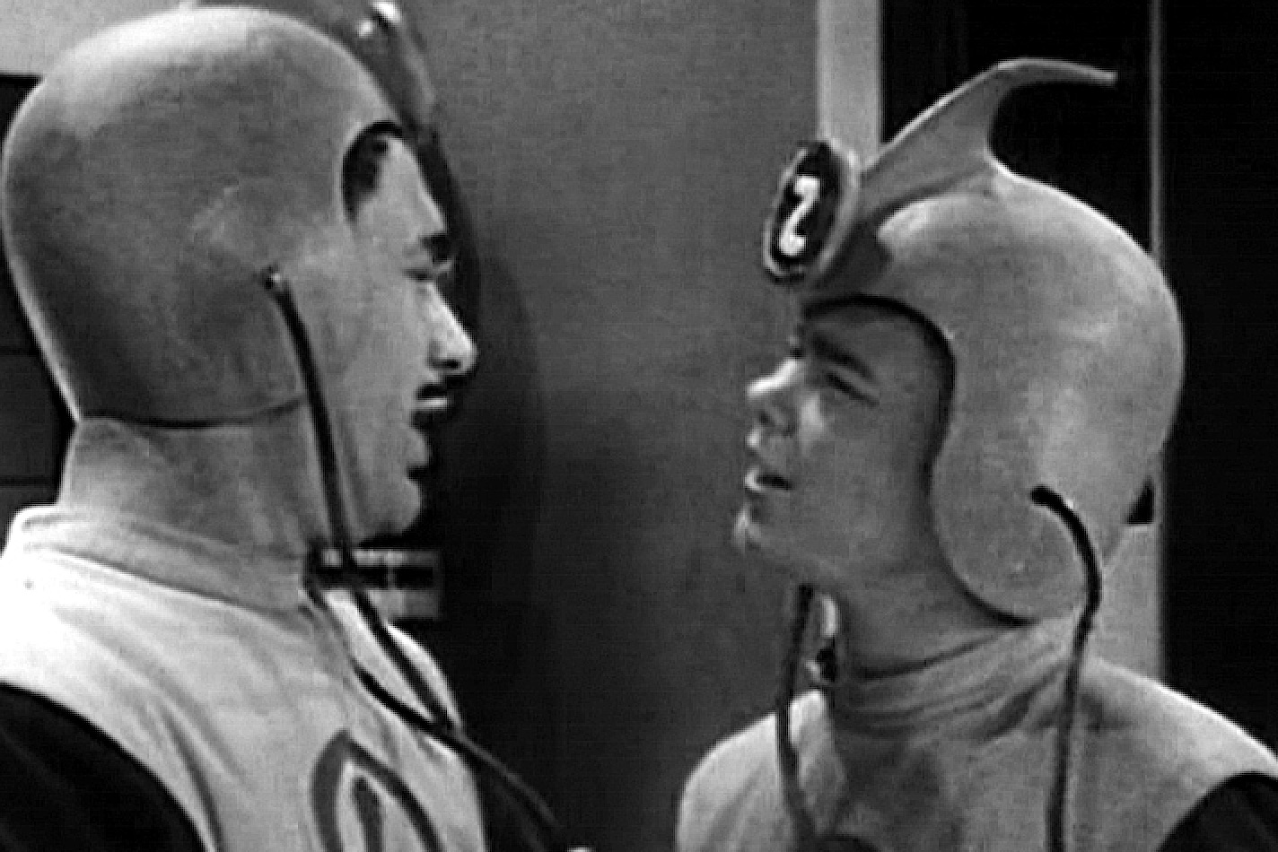 Two men in weird retro sci-fi outfits and helmets