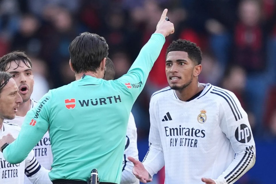 Jude Bellingham of Real Madrid receives a red card from a referee.