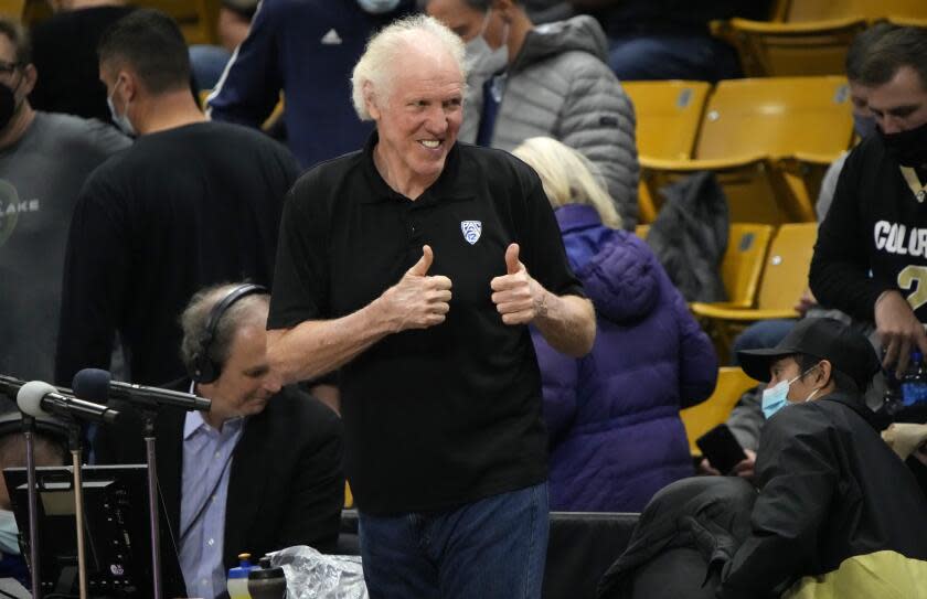 Television announcer Bill Walton acknowledges fans at an NCAA college basketball game.