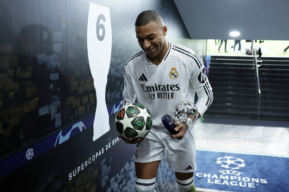 Kylian Mbappé holding awards and a soccer ball after a Champions League match.