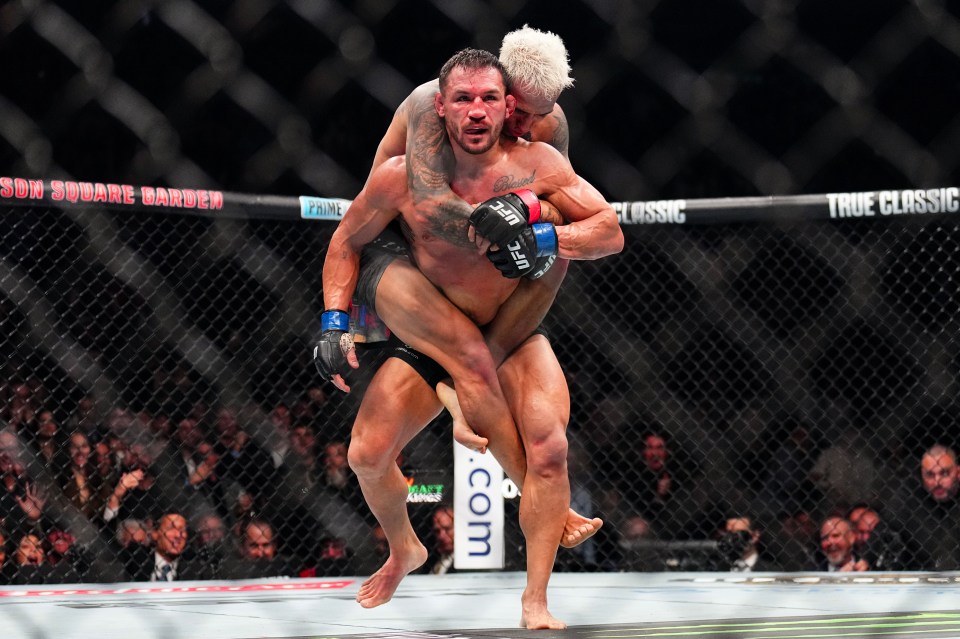 Michael Chandler carrying Charles Oliveira during a UFC fight.