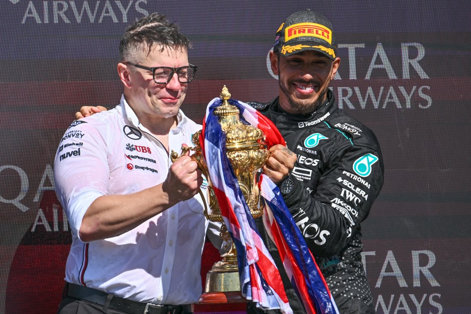 Lewis Hamilton and his race engineer celebrating a win with a trophy.