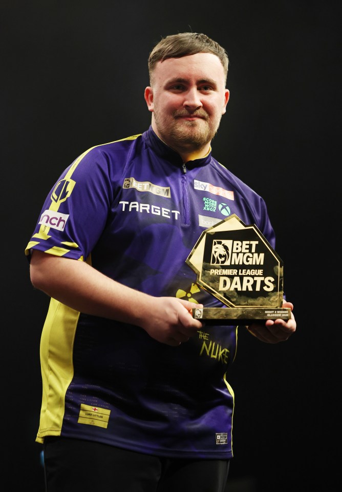 Luke Littler holding Premier League Darts trophy.