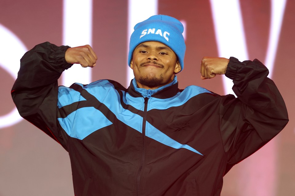 Shakur Stevenson flexing on stage before a boxing match.