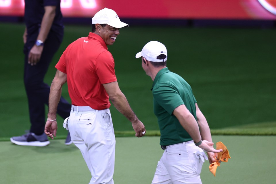 Tiger Woods and Rory McIlroy laughing during a golf match.