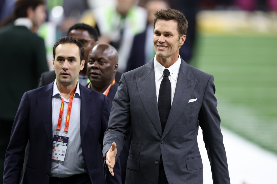 Tom Brady walking across a football field before a game.