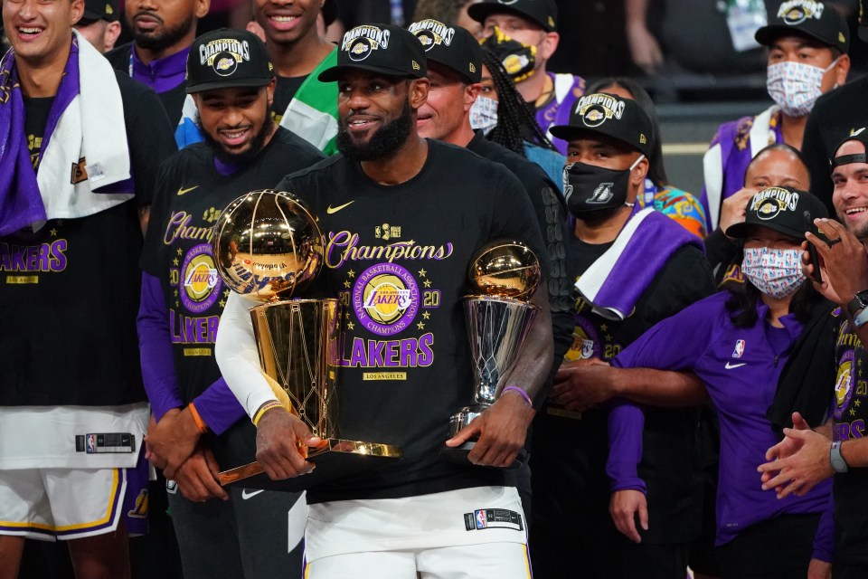 LeBron James holding the Larry O'Brien NBA Championship Trophy and the Bill Russell Finals MVP Award after the Lakers won the NBA Finals.