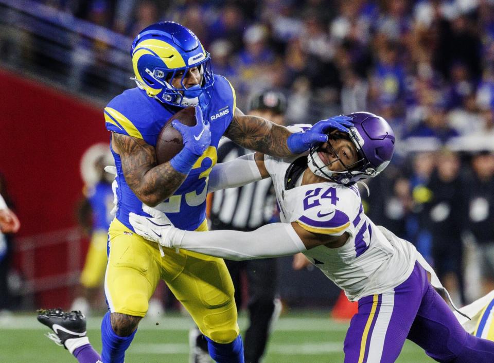 Rams running back Kyren Williams stiff arms Minnesota Vikings safety Camryn Bynum.