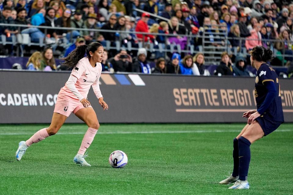 Angel City forward Christen Press dribbles the ball under Tension from Seattle Reign defender Phoebe McClernon.