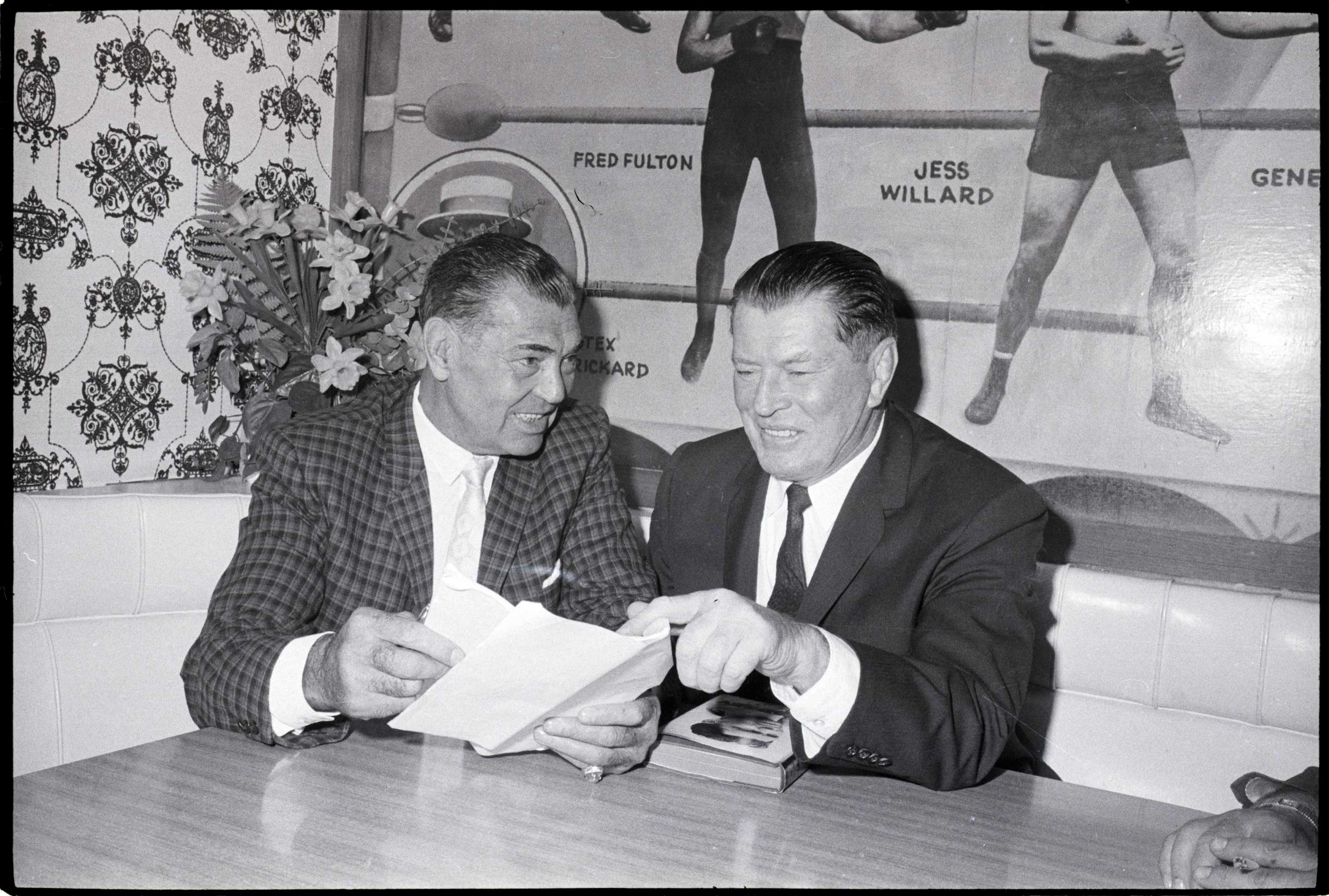 (Original Caption) 6/8/1960-New York, NY- Ex heavyweight champions Jack Dempsey (l) and Gene Tunney go over the script for a forthcoming TV show at Dempsey's Restaurant here, June 7. The TV show will be seen June 19, the day before the Patterson-Johansson title rematch. On the show, films of the Primary Patterson-Johansson fight will be shown, with Dempsey and Tunney serving as expert analysts of the action.